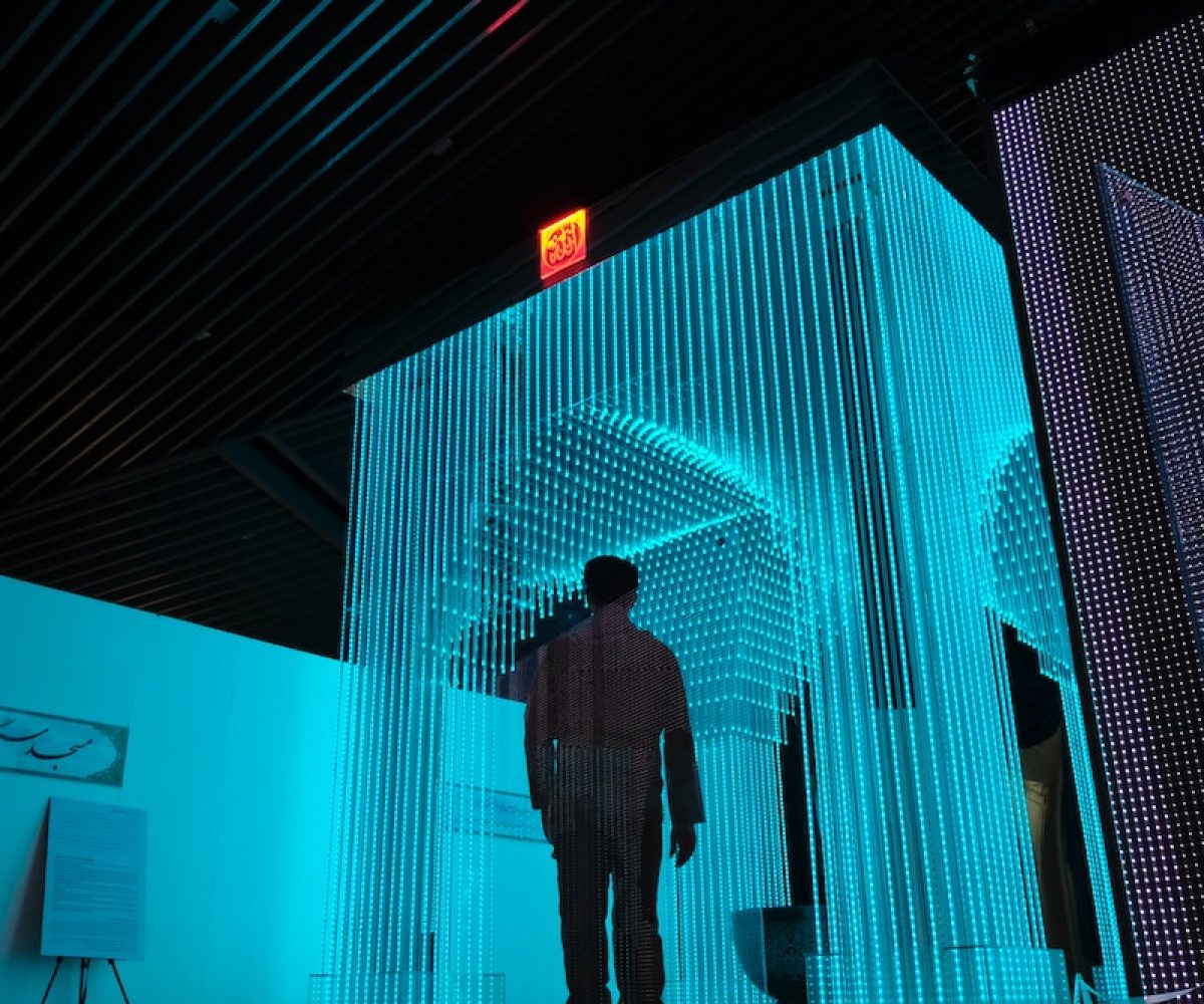 man in black jacket standing on blue lighted room